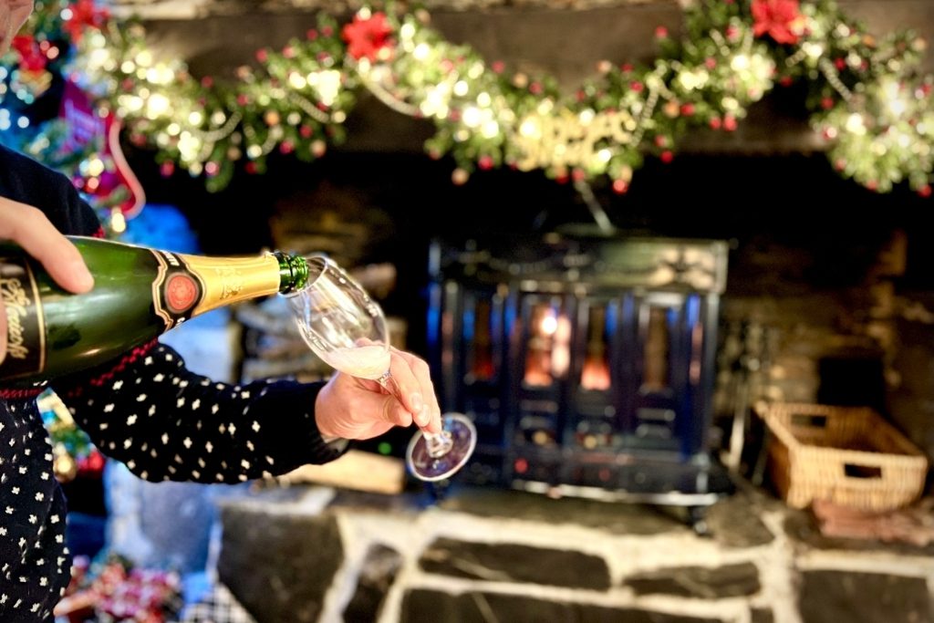 chritmas holiday cottage in brittany with wood burning stove, christmas garland and champagne being poured